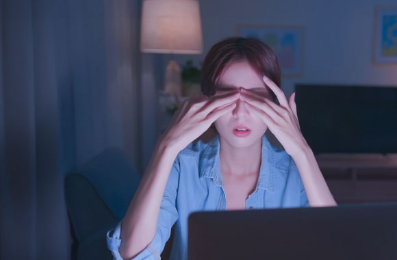 전자기기 블루라이트에 피곤해하며 양손으로 눈을 비비고 있는 여성 이미지